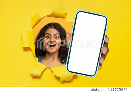 hindu lady holding phone in hand breaking through yellow backdrop hindu lady holding phone in hand breaking through yellow backdrop 111725683