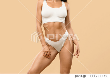Female Demonstrating Perfect Sporty Body In Underwear While Standing Against Beige Background 111725739