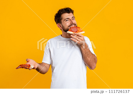 guy enjoys taste of pizza savoring junk food in studio 111726137