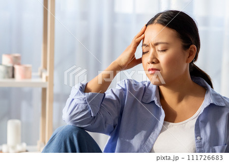 Asian woman with closed eyes touching her head Asian woman with closed eyes touching her head 111726683