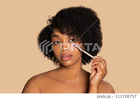 Woman applying eye makeup with brush, neutral tone Woman applying eye makeup with brush, neutral tone 111726757