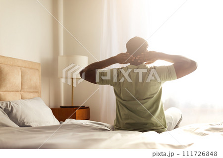 Rested african american man enjoying relaxed morning sitting on bed Rested african american man enjoying relaxed morning sitting on bed 111726848