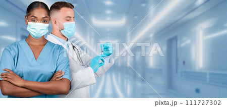 A male and female medical team in a hospital setting, with the man preparing a syringe 111727302