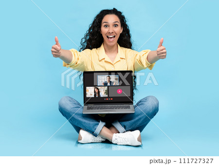 A cheerful young woman in a yellow shirt gives a double thumbs up while sitting A cheerful young woman in a yellow shirt gives a double thumbs up while sitting 111727327