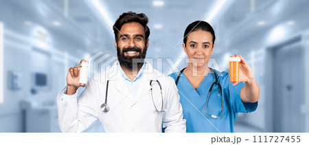 A male doctor and a female nurse, both with bright smiles, are presenting medication bottles 111727455