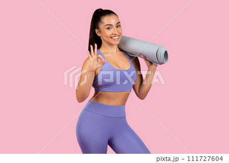 Happy yogi woman with mat makes okay sign, ready for class 111727604