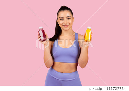 Confident woman presenting juice and smoothie bottles 111727784