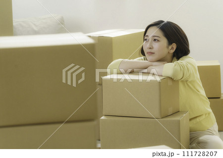 引越し作業中段ボールにもたれる疲れた若い女性 111728207