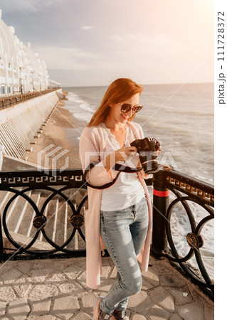 Woman summer travel sea. Happy tourist enjoy taking picture outdoors for memories. Carefree woman traveler posing on beach at sea on sunset, sharing travel adventure journey. Holiday vacation concept. Woman summer travel sea. Happy tourist enjoy taking picture outdoors for memories. Carefree woman traveler posing on beach at sea on sunset, sharing travel adventure journey. Holiday vacation concept. 111728372