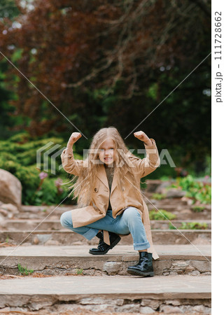 Seven year old girl makes faces in the spring in the park 111728662