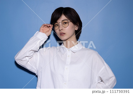 青背景で撮影をした眼鏡をかけた若い女性 111730391
