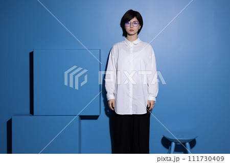 青背景で撮影をした眼鏡をかけた若い女性 青背景で撮影をした眼鏡をかけた若い女性 111730409