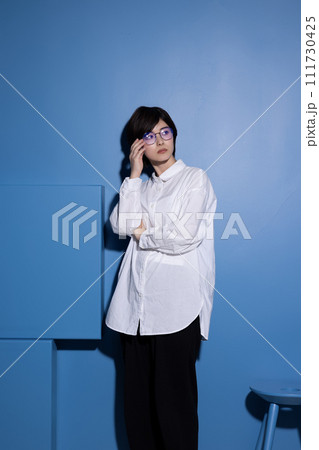 青背景で撮影をした眼鏡をかけた若い女性 111730425
