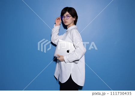 青背景で撮影をした眼鏡をかけた若い女性 青背景で撮影をした眼鏡をかけた若い女性 111730435