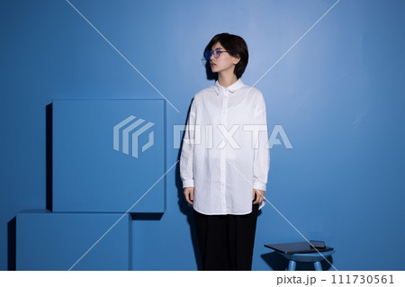 青背景で撮影をした眼鏡をかけた若い女性 111730561