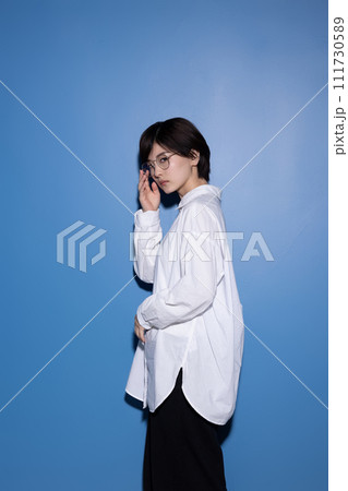 青背景で撮影をした眼鏡をかけた若い女性 111730589