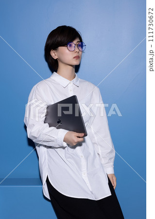 青背景で撮影をした眼鏡をかけた若い女性 青背景で撮影をした眼鏡をかけた若い女性 111730672