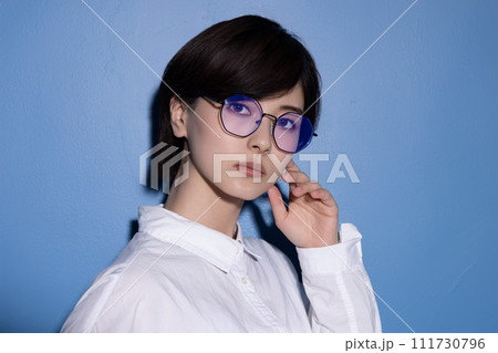 青背景で撮影をした眼鏡をかけた若い女性 111730796