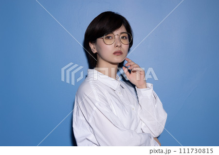 青背景で撮影をした眼鏡をかけた若い女性 青背景で撮影をした眼鏡をかけた若い女性 111730815