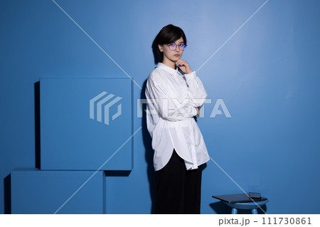 青背景で撮影をした眼鏡をかけた若い女性 青背景で撮影をした眼鏡をかけた若い女性 111730861