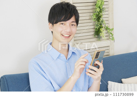 リビングでスマートフォンを使う男性 カメラ目線 リビングでスマートフォンを使う男性 カメラ目線 111730899