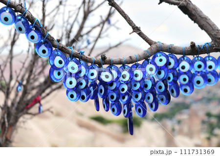 Many glass mascots - evil eye charms hang from a tree in Pigeon Valley, Cappadocia, Turkey Many glass mascots - evil eye charms hang from a tree in Pigeon Valley, Cappadocia, Turkey 111731369