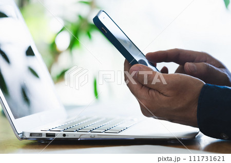 パソコンとスマホを操作する男性の手元 111731621
