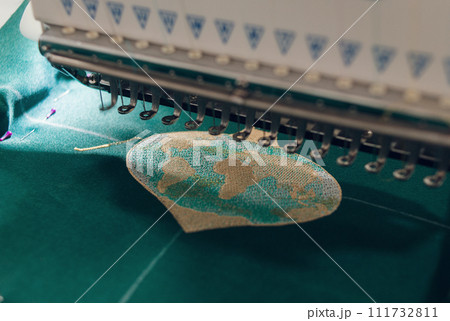 embroidery machine makes embroidery on green fabric embroidery machine makes embroidery on green fabric 111732811