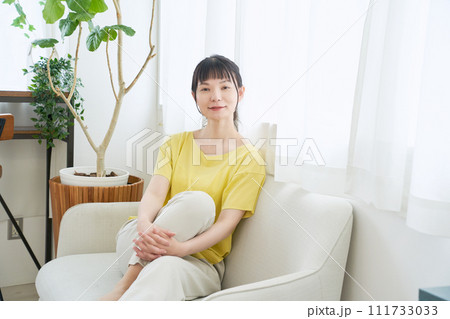 窓辺のソファーでくつろぐ女性 111733033