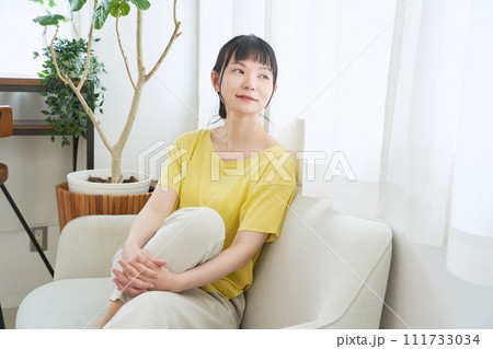 窓辺のソファーでくつろぐ女性 111733034