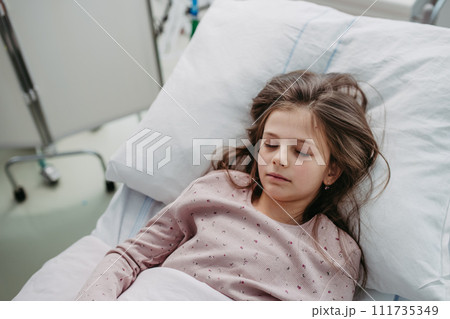 Little girl patient lying in hospital bed. Children in intensive care unit in hospital sleeping. 111735349