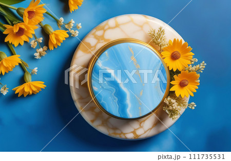 Empty round blue podium. Fresh yellow, orange color flowers around. Abstract geometrical form. Cylinder marble sphere, shadow. Blue golden background. Trendy showcase, display case. Place for showing 111735531