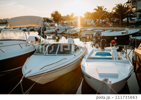 Small boats on calm water, moored in the harbor during sunset. 111735663