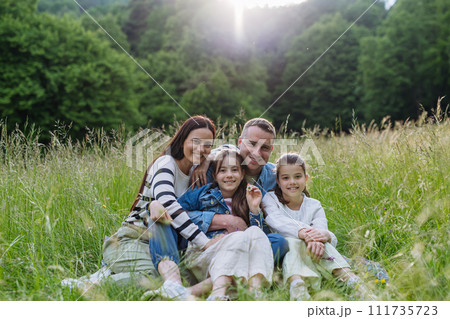 Beautfiul young family sitting in grass at meadow, enjoying together time. Beautfiul young family sitting in grass at meadow, enjoying together time. 111735723