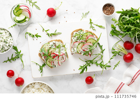 Sandwiches with rye bread toasts, cottage cheese, radish, cucumber, fresh greens and arugula for a healthy breakfast, top view Sandwiches with rye bread toasts, cottage cheese, radish, cucumber, fresh greens and arugula for a healthy breakfast, top view 111735746