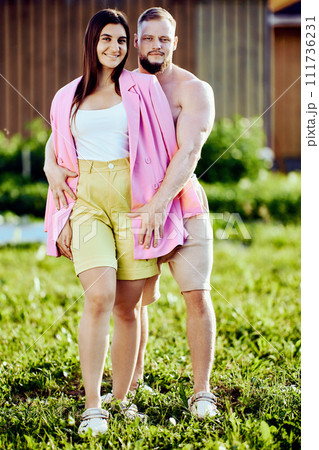 Summer photo session of married couple near country house, white young people are standing in garden. Summer photo session of married couple near country house, white young people are standing in garden. 111736231