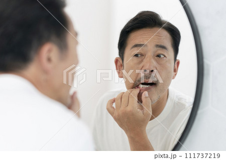 鏡で歯と歯茎をチェックする50代の男性 鏡で歯と歯茎をチェックする50代の男性 111737219