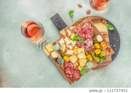 Cutting board with salami, cheese, olives and rose wine. top view. copy space for text 111737452