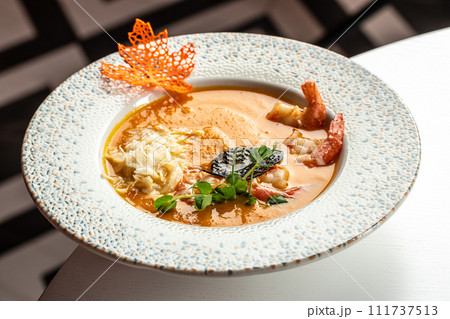 pumpkin soup with cream, shrimps in bowl on table pumpkin soup with cream, shrimps in bowl on table 111737513