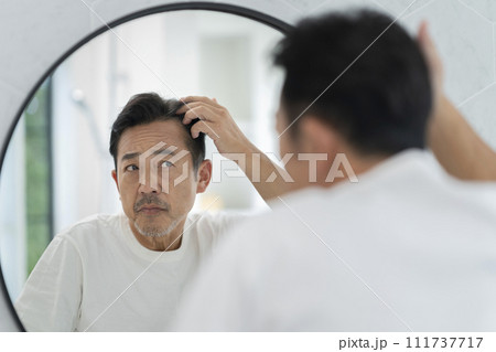 鏡を見ながら髪の生え際を気にする50代の男性 111737717
