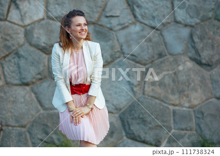 smiling modern woman in pink dress and white jacket in city smiling modern woman in pink dress and white jacket in city 111738324