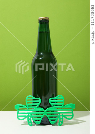 Green bottle and glasses on white table on green background Green bottle and glasses on white table on green background 111738663