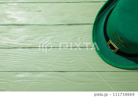 Green hat on green wooden background, space for text 111738669