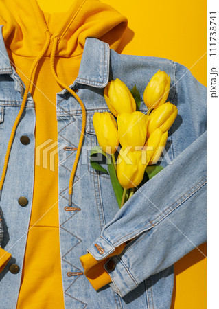 Hoodie, jeans jacket and flowers on yellow background, close up 111738741