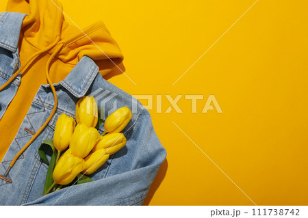 Hoodie, jeans jacket and flowers on yellow background, space for text 111738742
