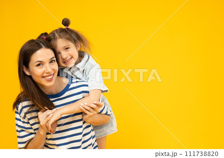 Mother and daughter are playing, on a yellow background. Mother and daughter are playing, on a yellow background. 111738820