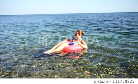 Summer vacation happy woman floats on an inflatable donut mattress, pink swim ring. Summer travel holidays vacation on the sea. 111738925
