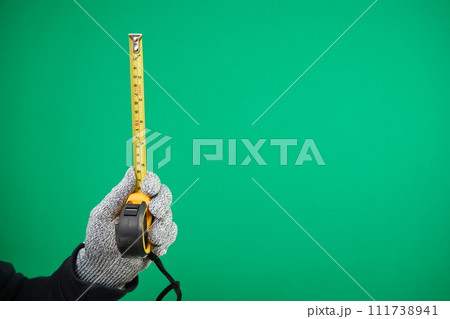 Close up view of Worker Man Hand with Tape Measure. Male Hand wearing Working cotton Glove with Tape-measure. Human hand holding tape measure. advertising Green background chromakey copy space Close up view of Worker Man Hand with Tape Measure. Male Hand wearing Working cotton Glove with Tape-measure. Human hand holding tape measure. advertising Green background chromakey copy space 111738941