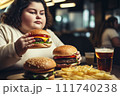 Fat girl eating hamburger in fast food restaurant.  111740238