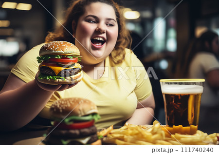 Fat girl eating hamburger in fast food restaurant.  111740240